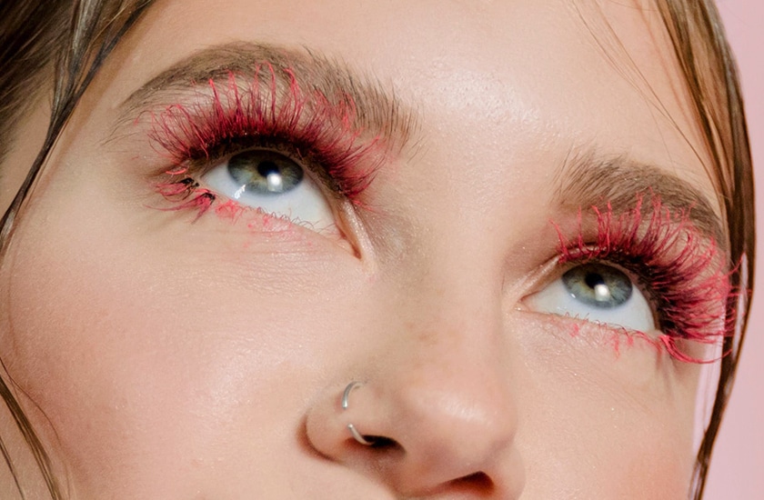 Foco nos olhos de uma mulher com cílios grandes e coloridos 