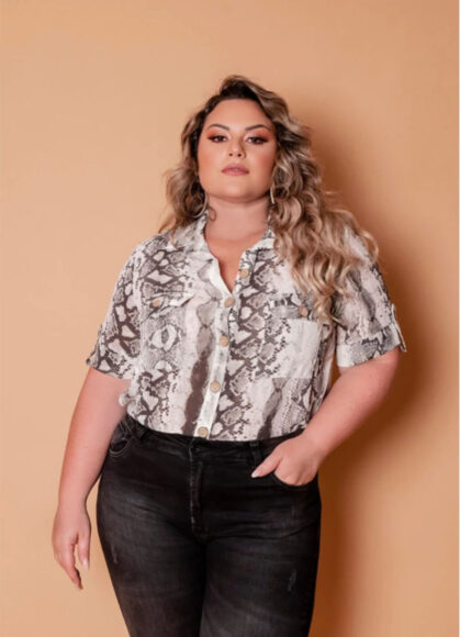 Uma mulher usando um camisa com animal print de onça e calça jeans escura 