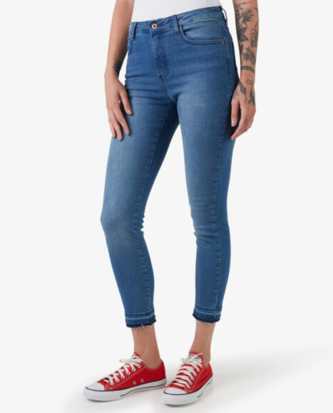 Uma mulher usando calça jeans cigarrete escura e um all star vermelho 