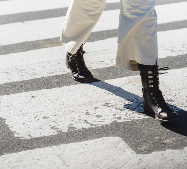 foco numa bota de cano médio atravessando a rua numa faixa de pedestre