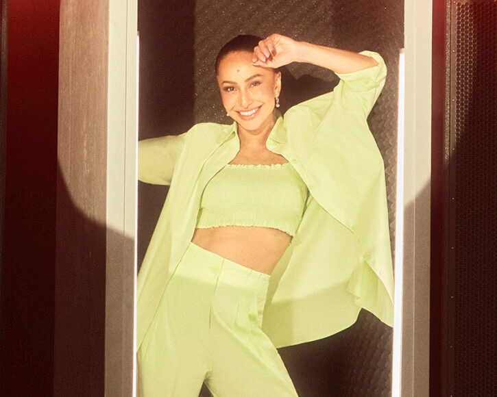 mulher com expressão sorridente usando um look monocromático verde 