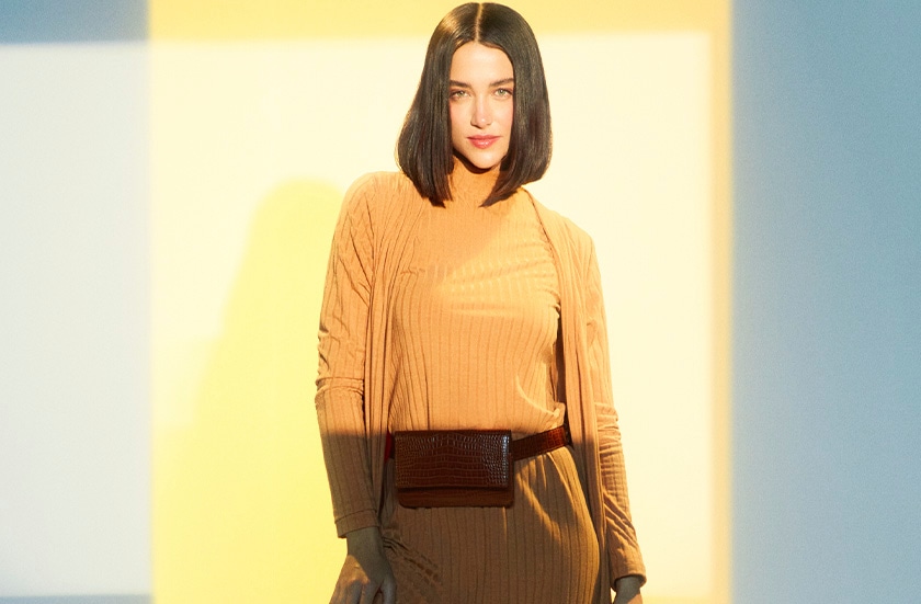 mulher com uma expressão mais séria usando um look monocromático alaranjado