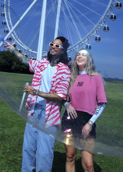 casal em um festival de música em frente a uma roda gigante