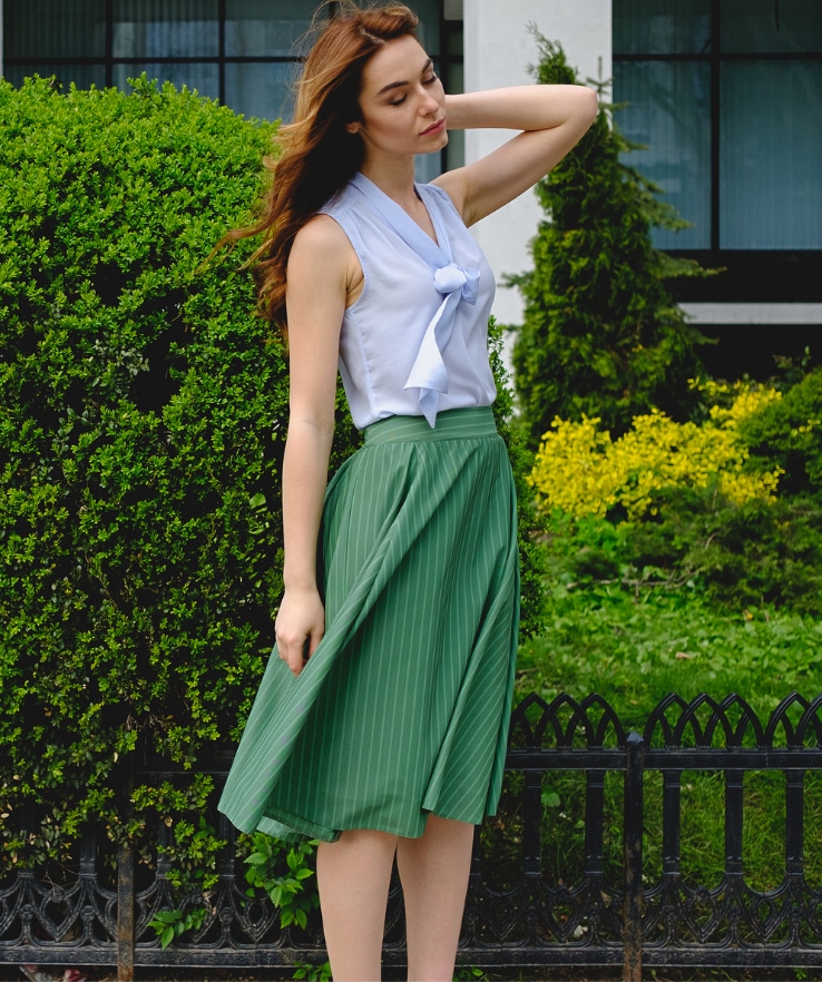 mulher usando um look com saia midi verde e blusa branca